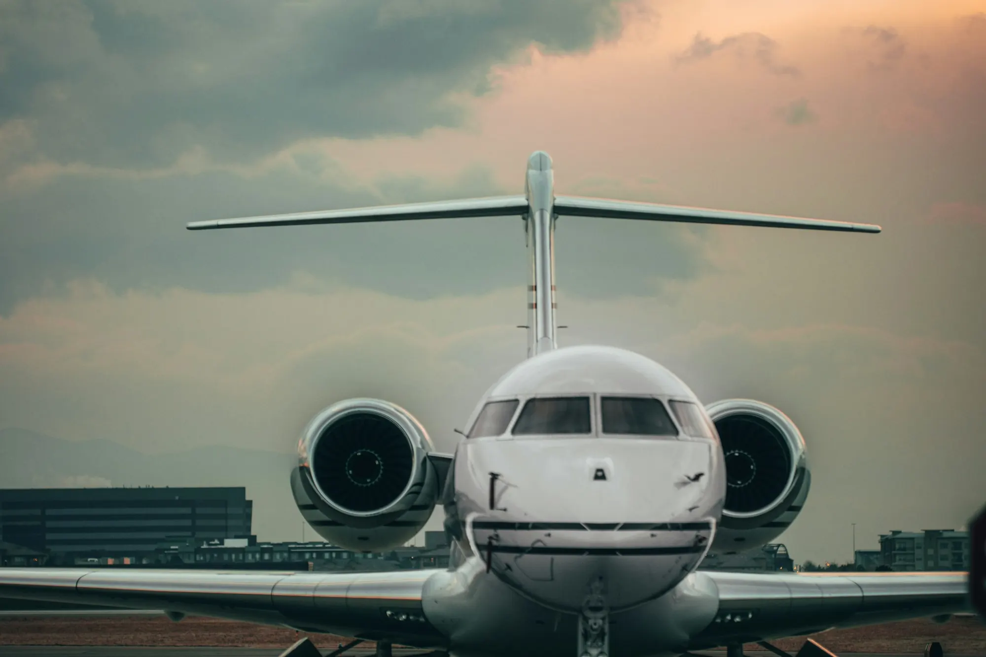 A light business jet taxiing at dusk, seen head-on