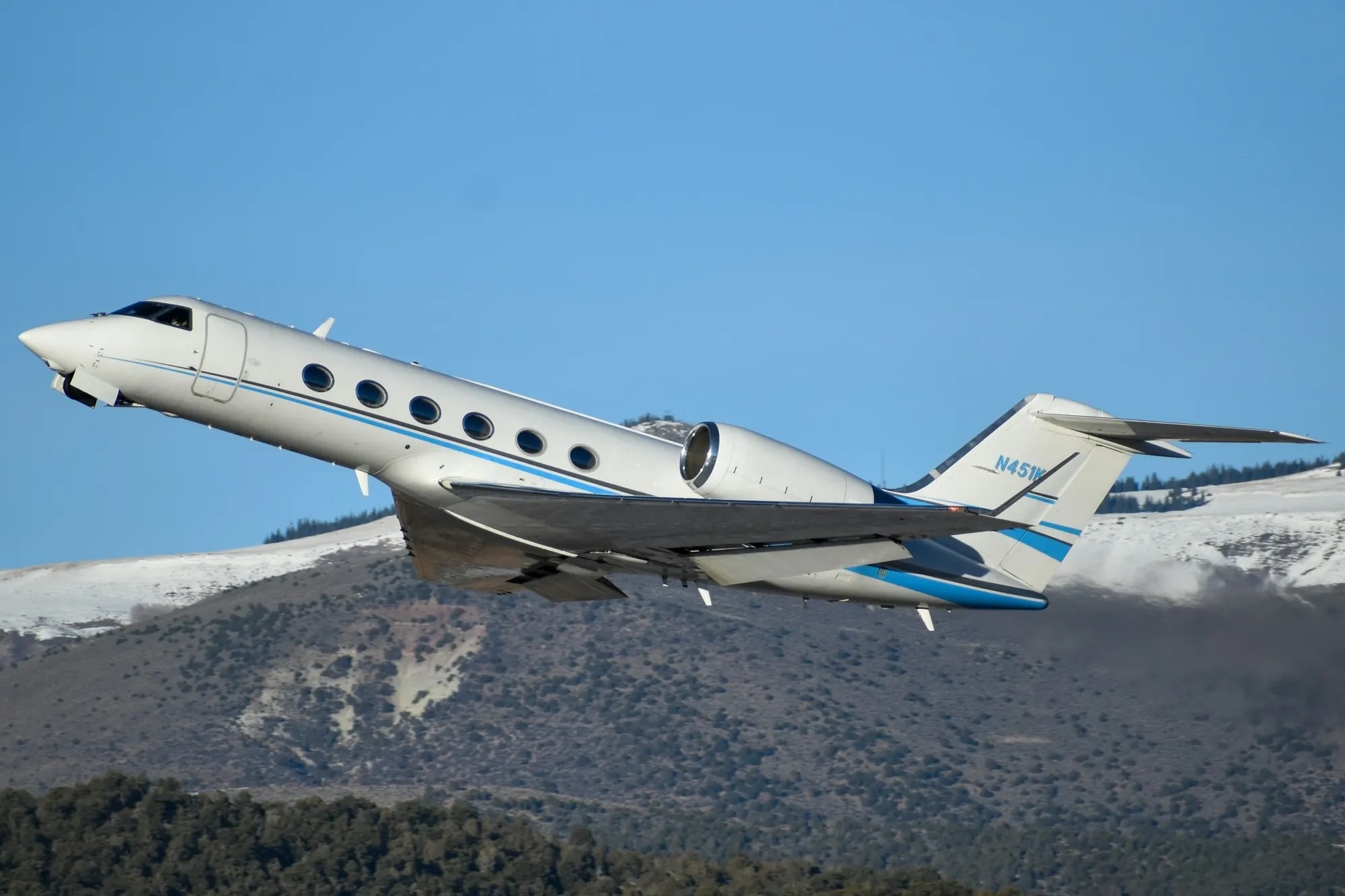 A business jet in flight above snow-covered mountains